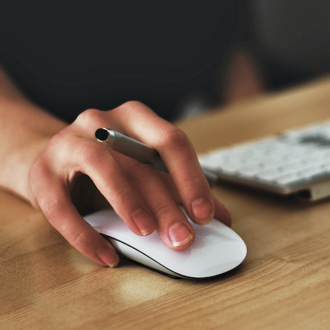 Closeup of hand holding a pen and using an Apple mouse