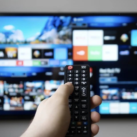 Hand holding a remote in front of a CTV device