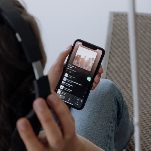 Person listening to programmatic audio ads via Spotify on their smartphone with over the ear headphones on