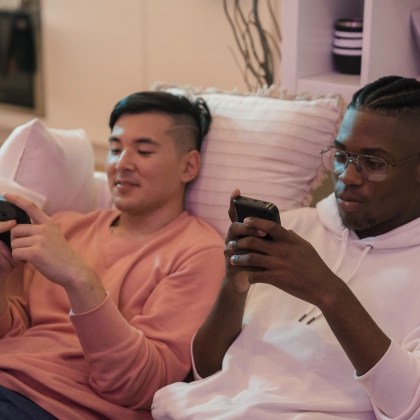 Two friends sitting on a couch staring at mutli-channel advertising on their smartphones