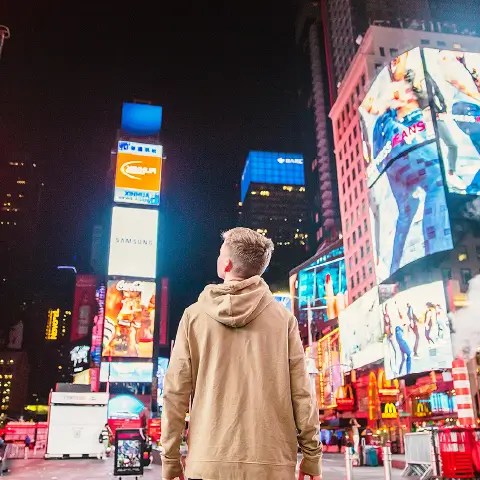 Person staring up at multi-channel advertisements in Time's Square